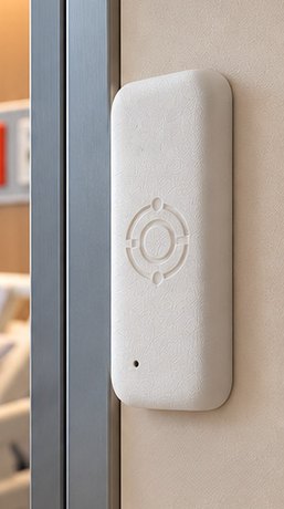 A VAKT node mounted on a wall beside a hospital room doorway